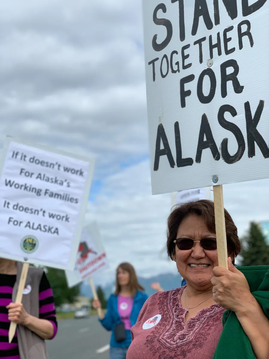 Three people holding rally signs
